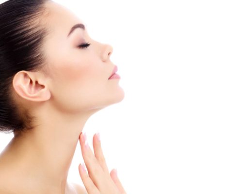 Young female touches her neck, white background